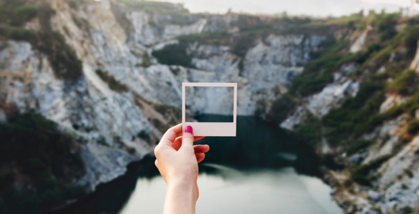 woman holding up a photo frame at a valley